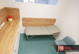 Behandlungsraum mit maßgefertigter Liege und durchdachter Ausstattung in ruhiger Farbgebung.