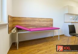 Die gepolsterte Liege in kräftigem Pink und die robuste Rückwand in Holzoptik sind nicht nur ein Hingucker, sondern auch hygienisch durchdacht und funktional platziert.