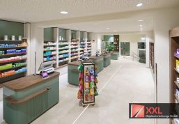 Ein Blick in den Verkaufsraum: Lichtdurchflutete Räume mit eleganten Holz- und Grüntönen sorgen für ein modernes, freundliches Ambiente und laden zum Verweilen ein.