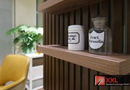 Ein Hauch von Tradition: Stilvolle historische Apothekengläser setzen elegante Akzente und unterstreichen die lange Tradition der Pharmazie. In Kombination mit der warmen Holzoptik und der modernen Einrichtung schafft dieses Detail eine einladende Atmosphäre – perfekt für eine Apotheke, die Tradition mit modernem Service verbindet.