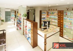 Gesamtansicht der maßgefertigten Apothekeneinrichtung mit Handverkauf und umlaufender Regalierung.