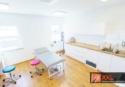 Großzügig geschnittener Laborraum mit modernen Arbeitsflächen, farbigen Hockern und Untersuchungsliege – für effiziente und hygienische Abläufe im Praxisalltag.