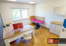 Holzelemente, farbige Liegeflächen und strukturierte Arbeitsbereiche schaffen eine einladende Atmosphäre im Behandlungszimmer – mit viel Platz und Licht.
