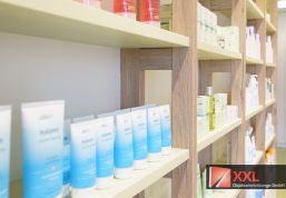 Holzelemente vor dezent-grünem Ablagen sorgen für einen natürlichen Esprit bei den Regallösungen der Kreuz Apotheke Löbejüne