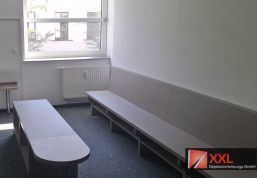 Raumhoch angepasste Wandbank mit Rückenlehne und passendem Tisch für eine platzsparende Wartesituation.